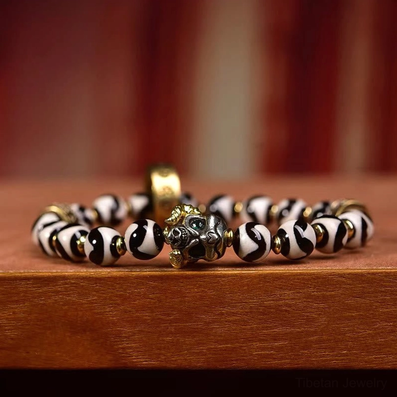 Side view of Nine-Eye Dzi Bead bracelet with hand-engraved copper rings and black-white patterned protective amulet beads