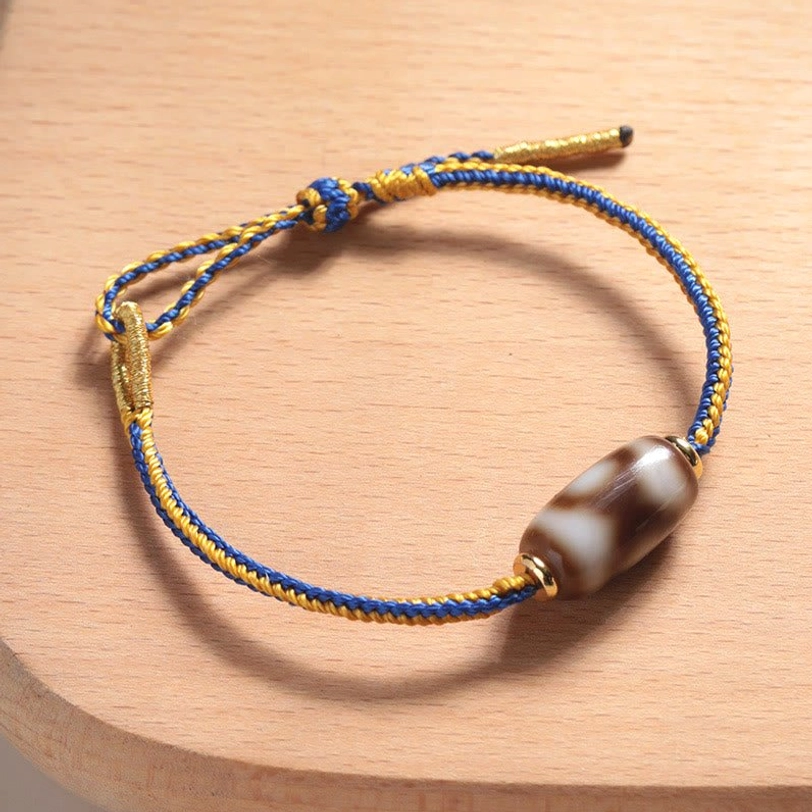 Three-eye Dzi bead bracelet side view, detailed look at cylindrical agate bead with authentic eye patterns and gold hardware