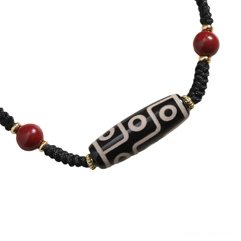 Tibetan nine-eye dzi bead bracelet front view showing symmetric red beads and neatly braided black cord