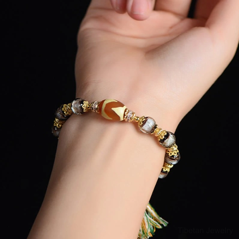 Close-up side view of Dzi blessing bracelet worn on wrist showing fit and gold decorative details