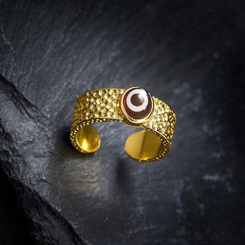 Top-down view of nine-eye Dzi bead ring on dark stone background displaying full pattern