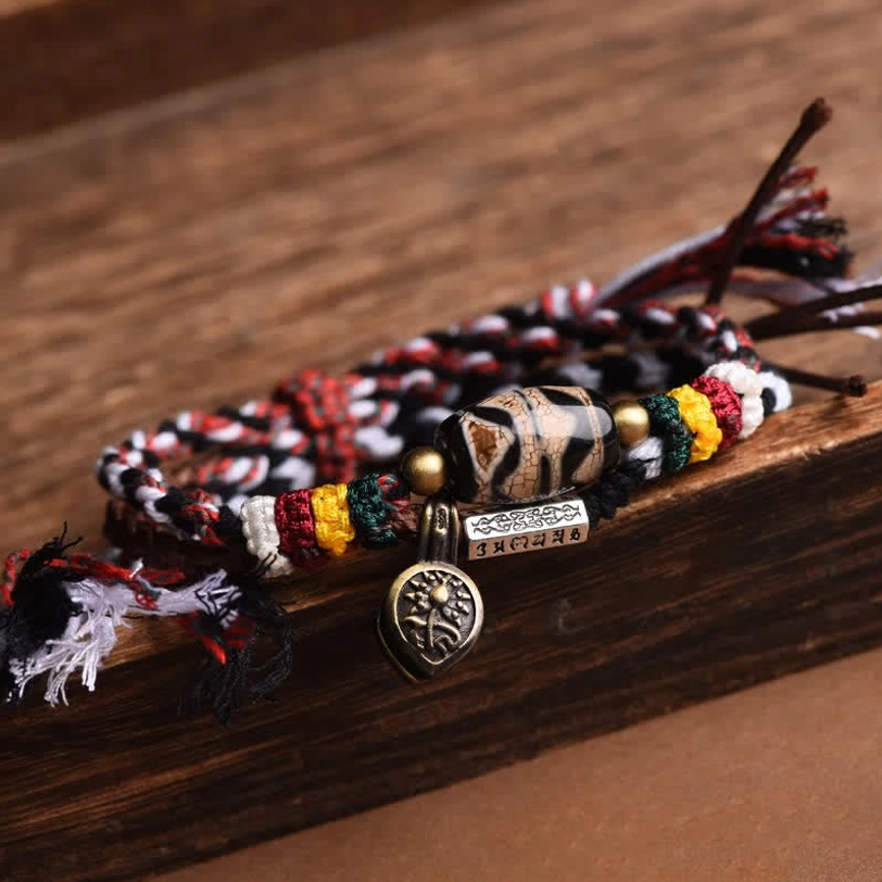 Tibetan Dzi bead Om Mani Padme Hum bracelet detail showing hand-painted bead pattern and braided cord weave