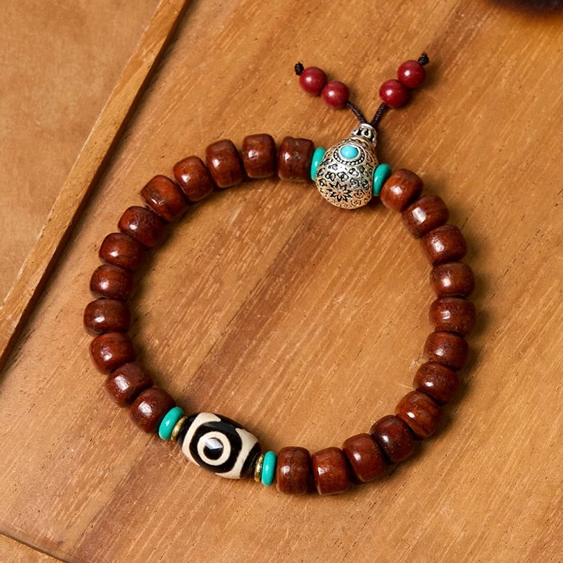 Handmade Dzi bead mala bracelet with barrel brown beads and silver ornament flat lay