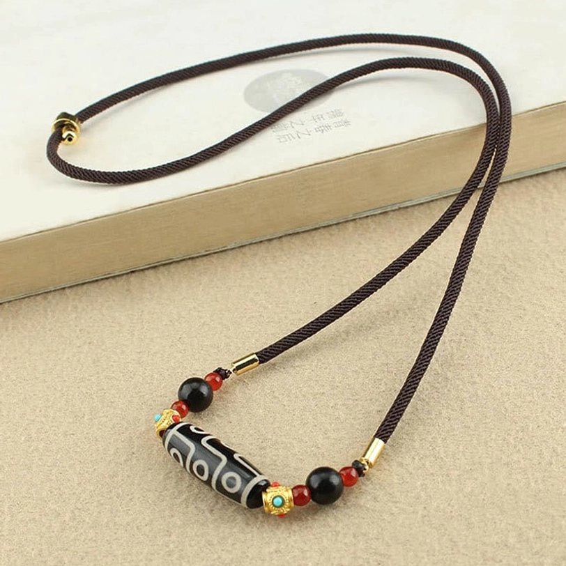 Tibetan dzi bead necklace with slim black braided rope minimal beads on light tabletop