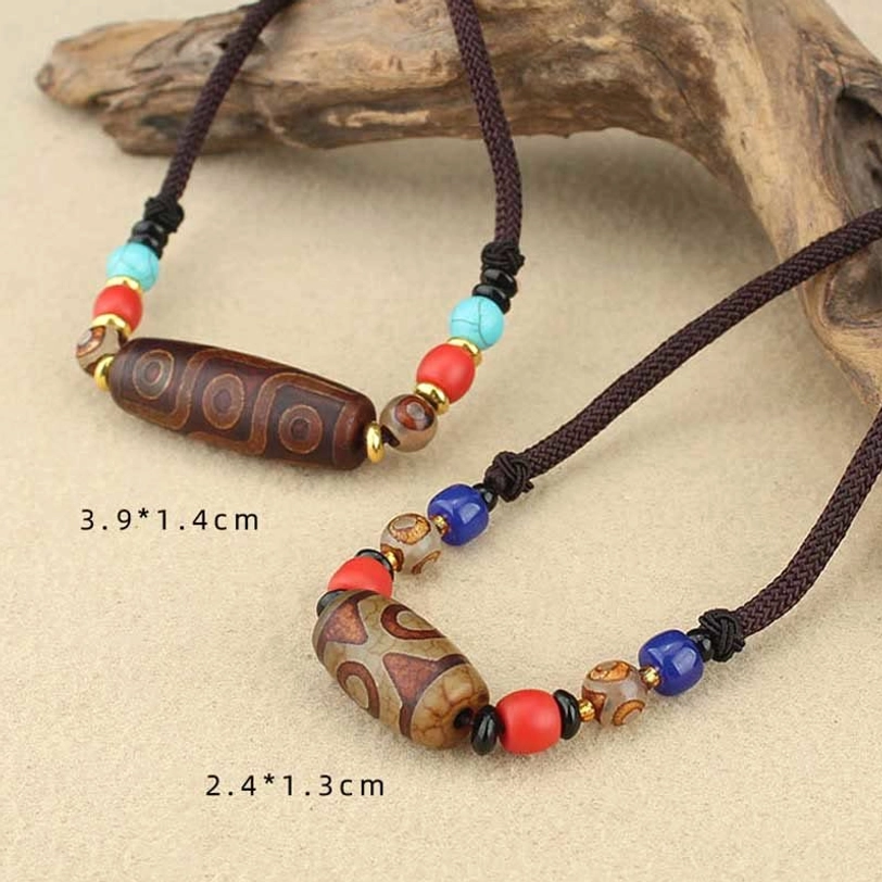 Two dzi bead protection necklaces top-down view showing different sizes and eye patterns with size measurements on driftwood background