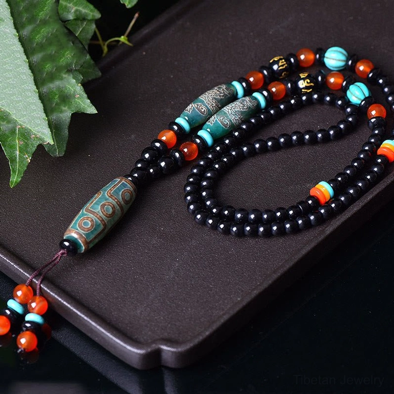 Tibetan Dzi Bead Protection Necklace overhead angled view showing etched dragon patterns and sacred beads