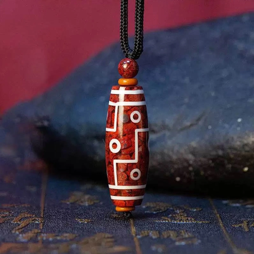 Cinnabar dzi bead necklace with nine-eye pattern featuring red base with white line and circle designs, black rope with wooden spacers