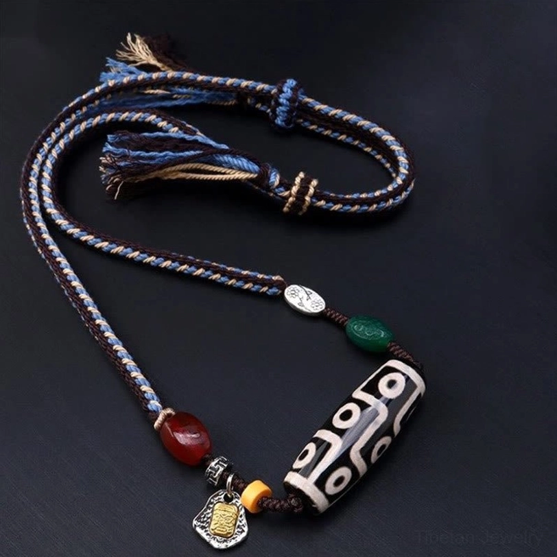 Tibetan nine-eye dzi bead braided necklace overhead view with mixed-color cord and decorative beads