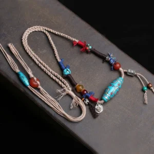 Tibetan dzi bead necklace detail shot showing linen cord and turquoise beads with metal charm tassel