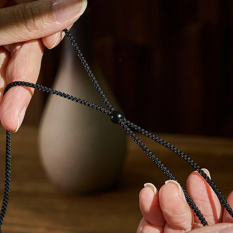 Hands holding tibetan agate dzi bead necklace demonstrating adjustable fit and wearable comfort