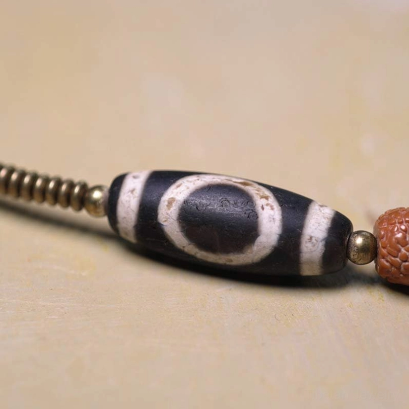 Traditional Nine-Eye Dzi Bead featuring classic eye pattern and metal spacer beads in protective amulet design