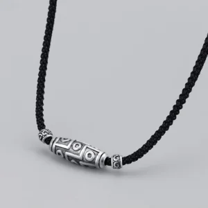 Tibetan Nine-Eye Dzi bead pendant on silver rope necklace, oblique angle displaying decorative silver spacers and adjustable cord