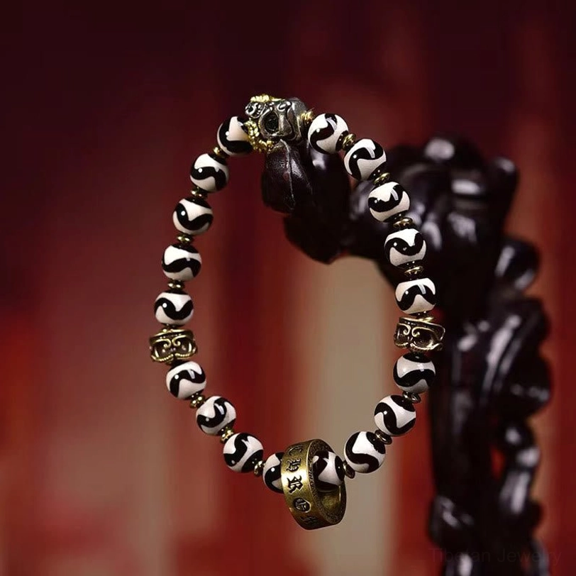 Full side profile of Dzi Bead Om Mani Padme Hum bracelet against red display background, showcasing multiple carved brass spacers and sacred beads