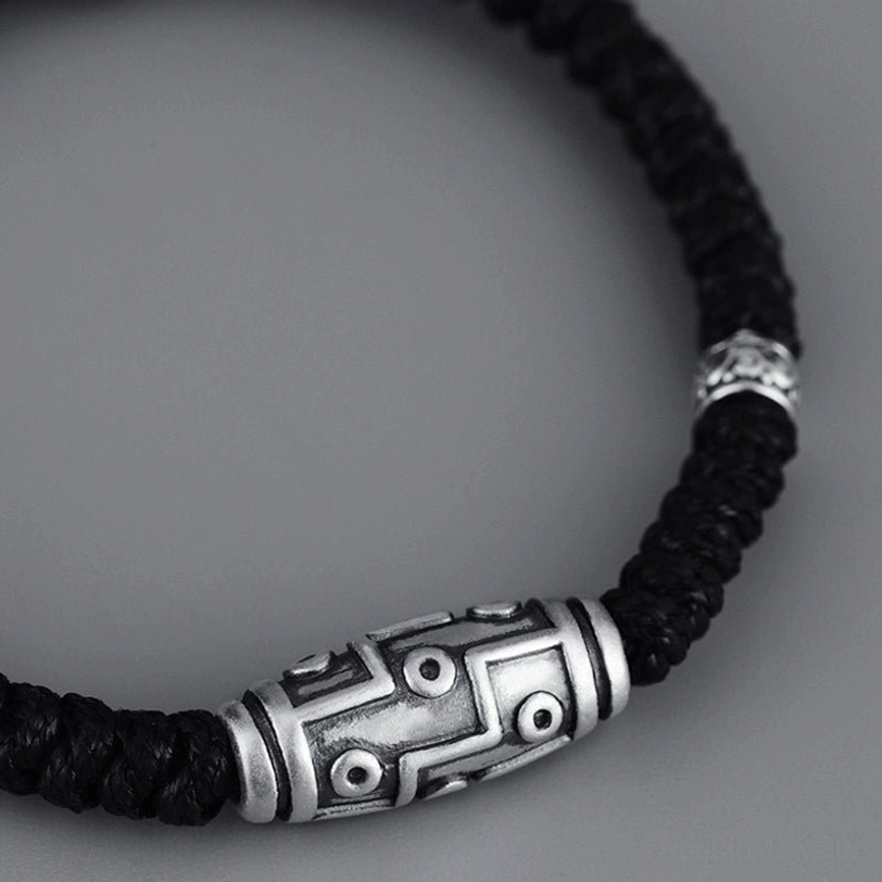 Sterling silver dzi bead bracelet angled side close-up, showcasing engraved nine-eye pattern and silver accent bands