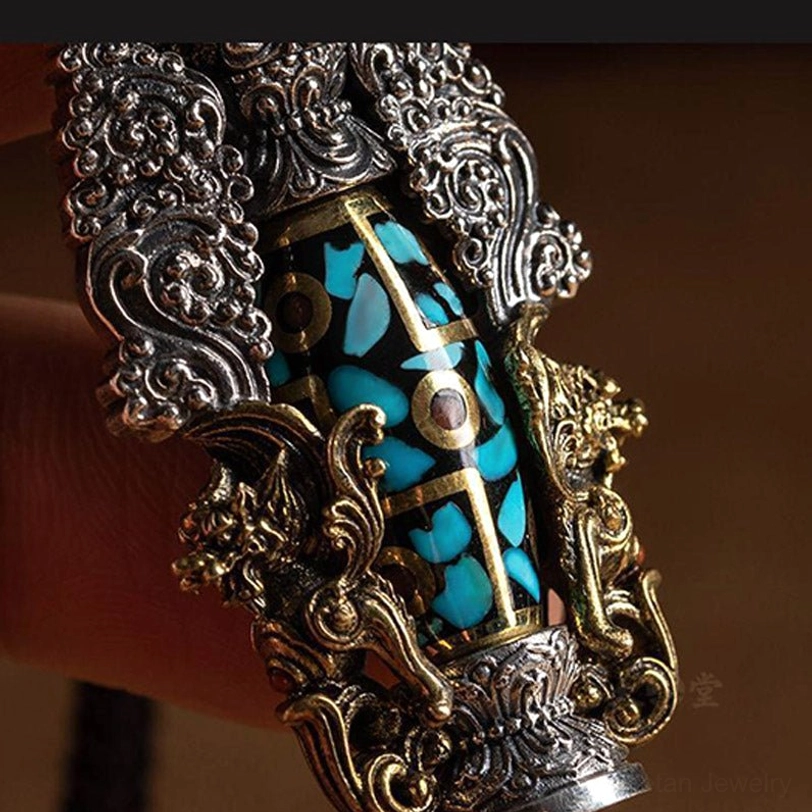 Extreme close-up of dzi bead turquoise and metal mosaic inlay pattern showing gold and silver mixed metalwork and intricate details