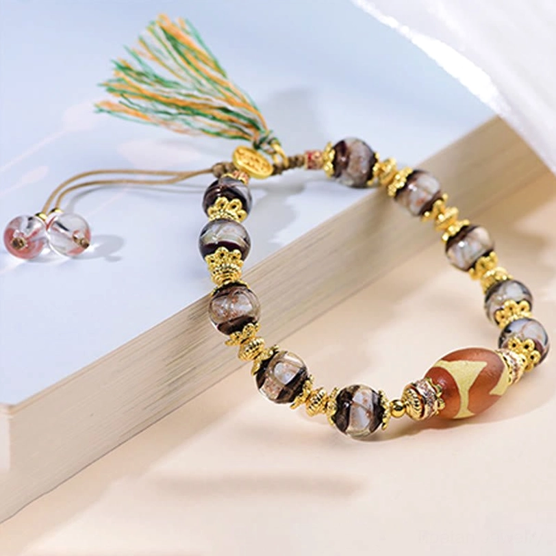 Nine-Eye Dzi bead bracelet flat lay showcase with premium Liuli glass and green tassel decoration