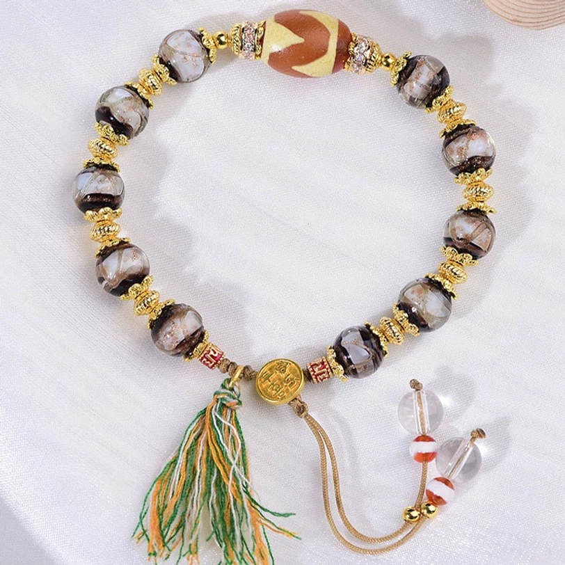 Liuli glass Dzi bracelet overhead view showing adjustable elastic cord and crystal accents with gold charm