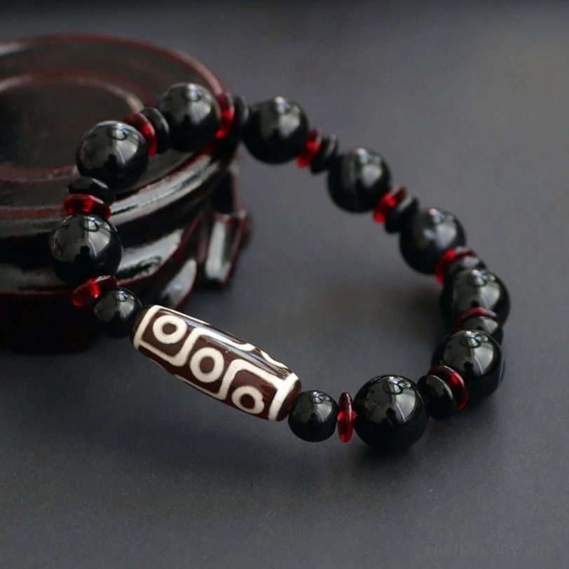 Side angle view of hand-painted Nine-Eye Dzi Bead bracelet demonstrating bead placement and the glossy finish of natural black onyx stones
