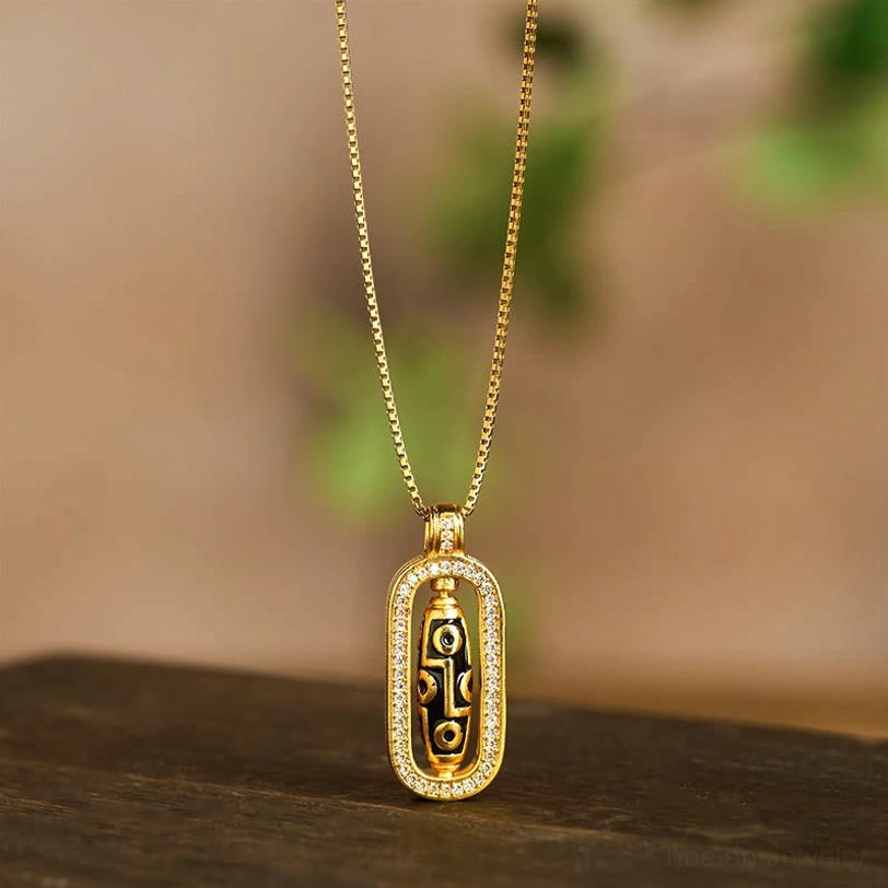 Rotatable nine-eye dzi bead pendant close-up on wooden table with green bokeh background, front view