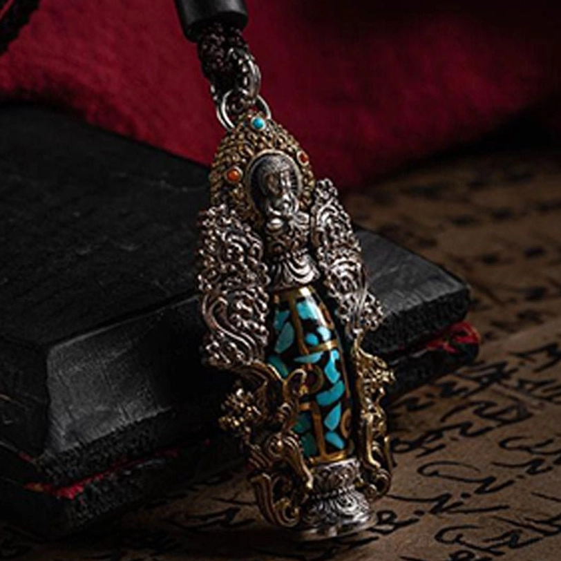Tibetan dzi pendant side close-up displayed on vintage script paper with black box, featuring turquoise mosaic inlay and ornate silver frame