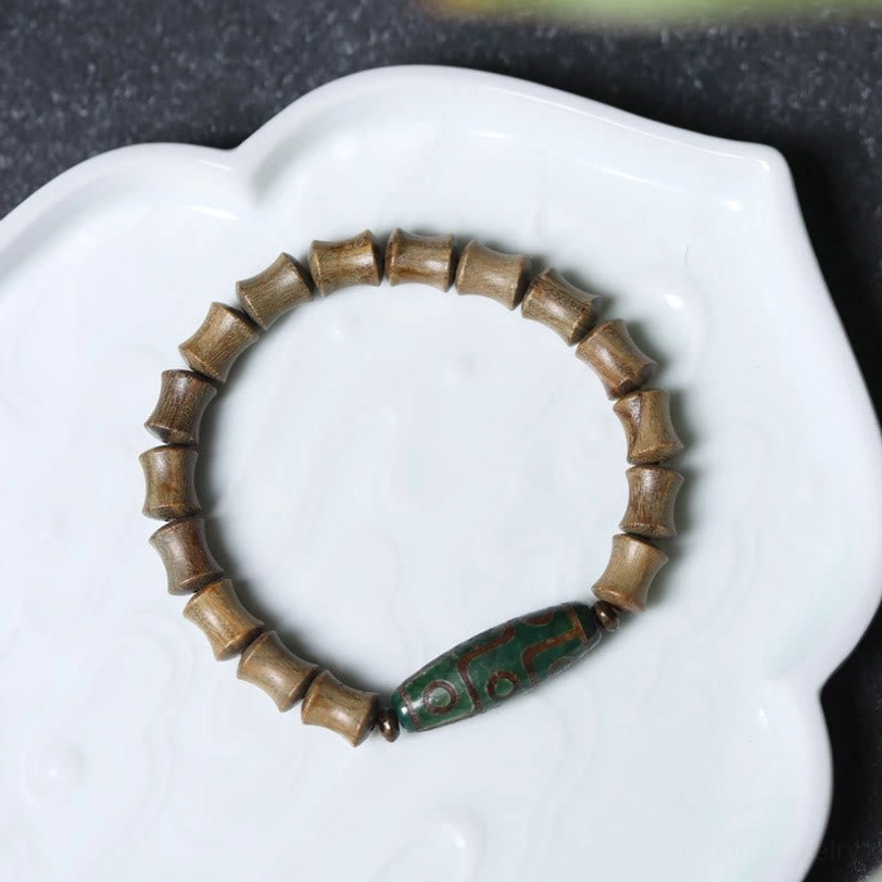 Complete nine-eye dzi green sandalwood bracelet full circle overhead view on white ceramic tray unobstructed