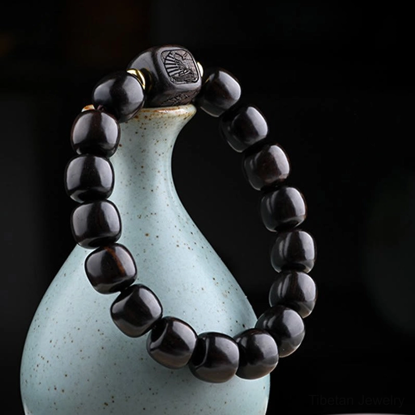 Close-up detail of ebony wood barrel beads bracelet with matte black wood tone and carved decorative elements