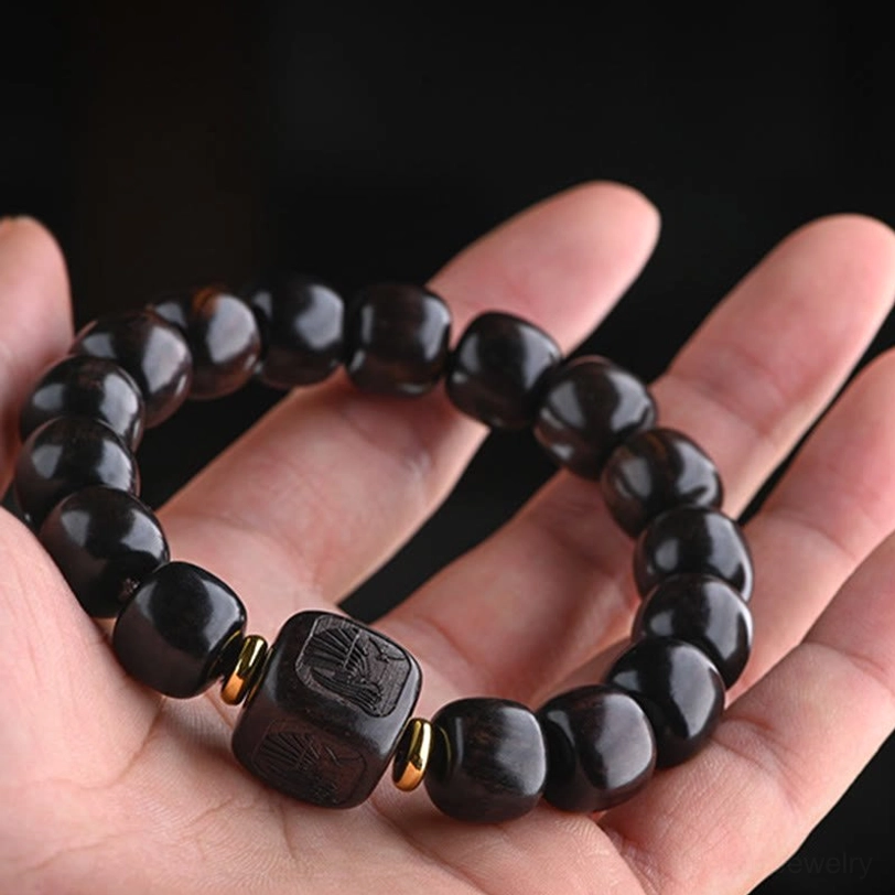 Tibetan ebony wood barrel bead bracelet side view in hand showing matte dark wood surface and metal accents
