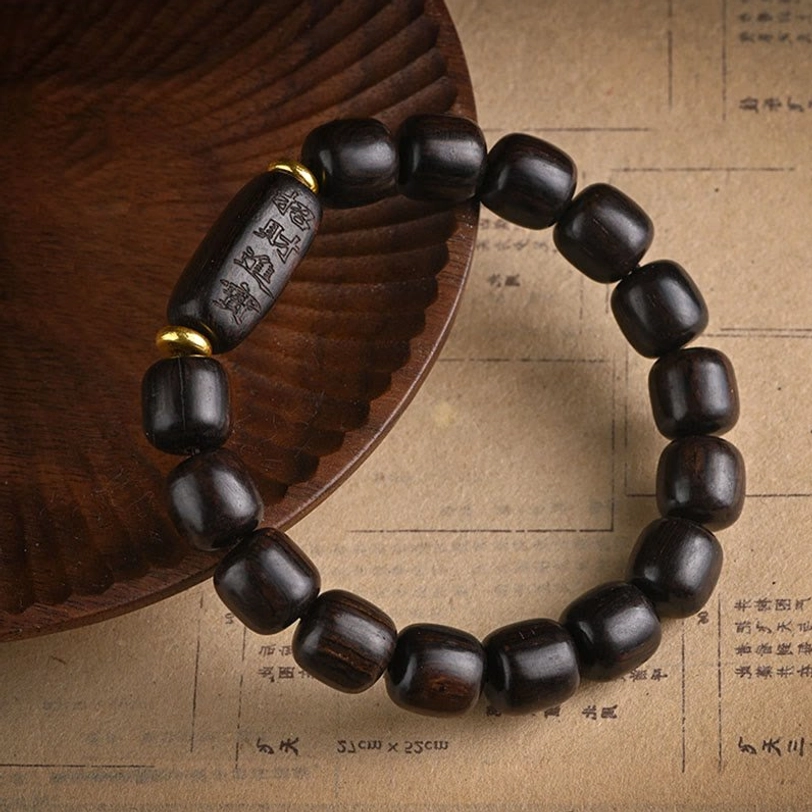Tibetan ebony wood barrel bead bracelet with long carved accent bead and brass spacers on vintage background