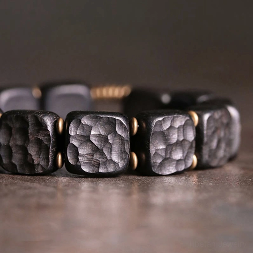 Detailed macro shot of ebony wood bead texture showing hammered surface with bronze gold round spacers