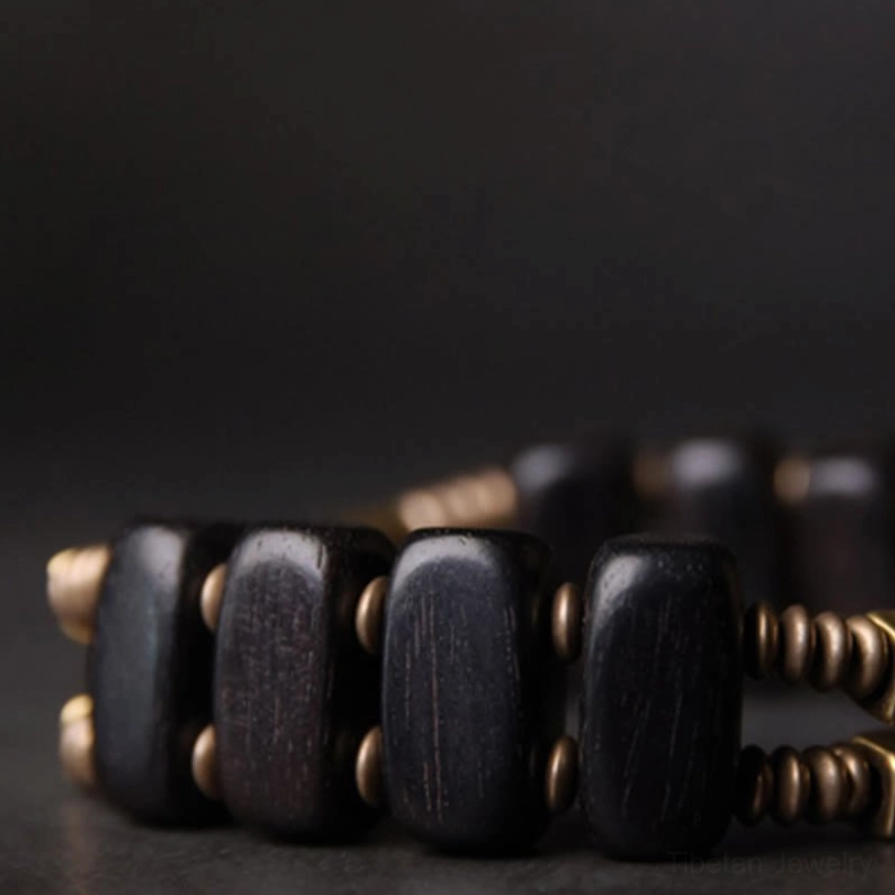 Close-up detailed view of double layer ebony brass bracelet on dark grey desktop background, featuring square dark ebony beads with brass round spacers and detailed metal joints