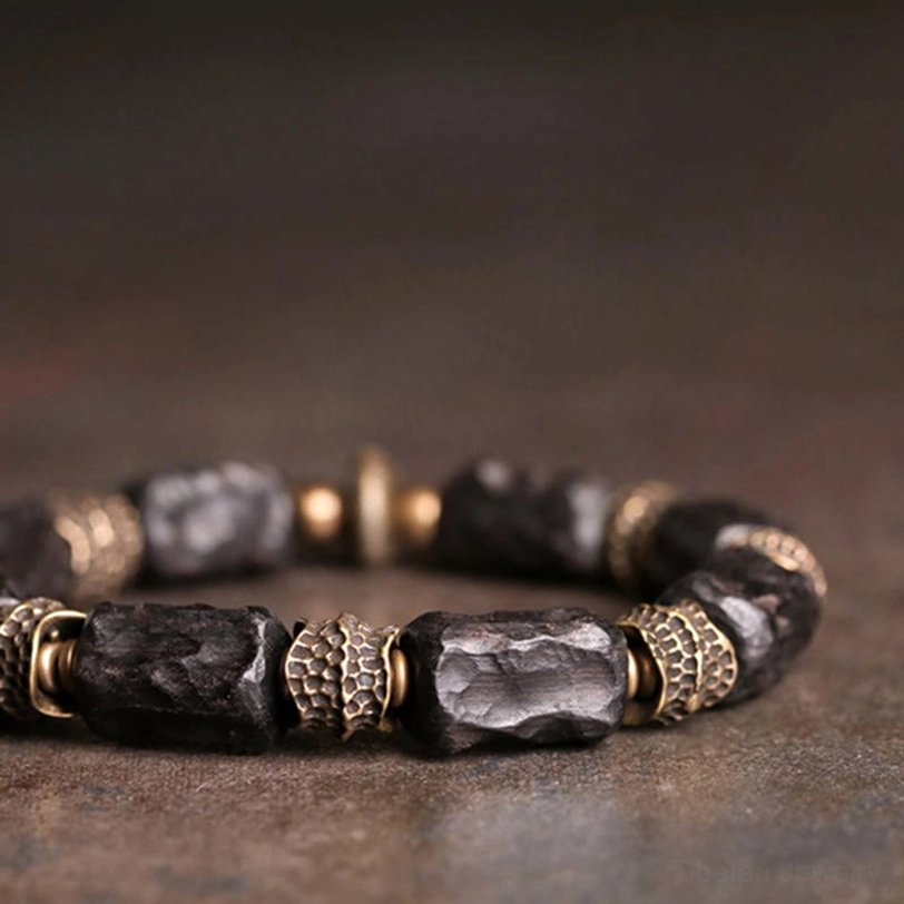 Close-up side view of ebony copper bracelet showing detailed wood grain texture and carved brass spacer details against dark background