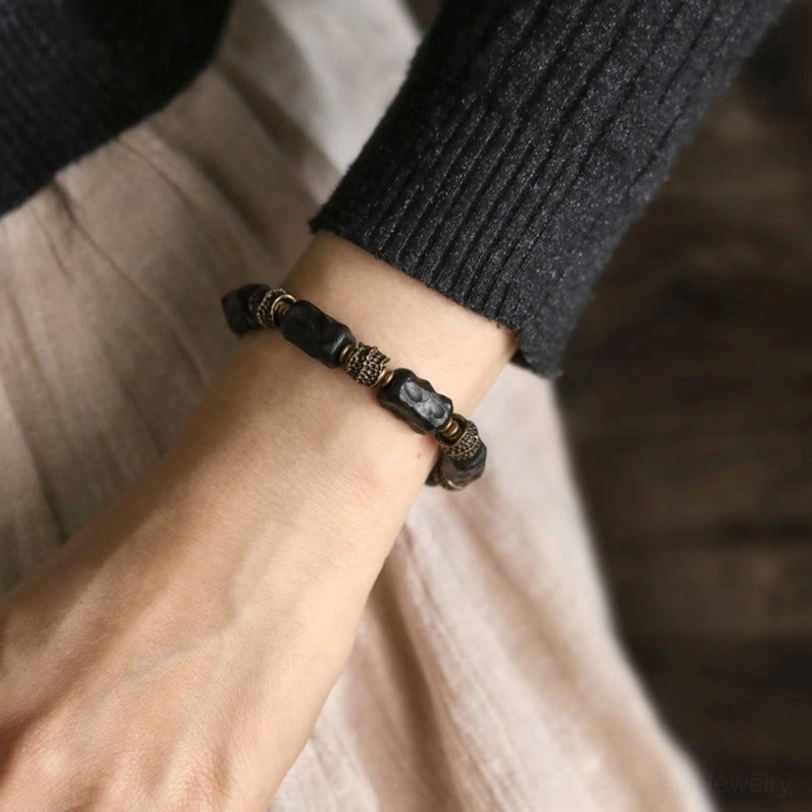 Ebony copper beaded bracelet worn on wrist with knit sleeve layered outfit showing slim bracelet style casual aesthetic