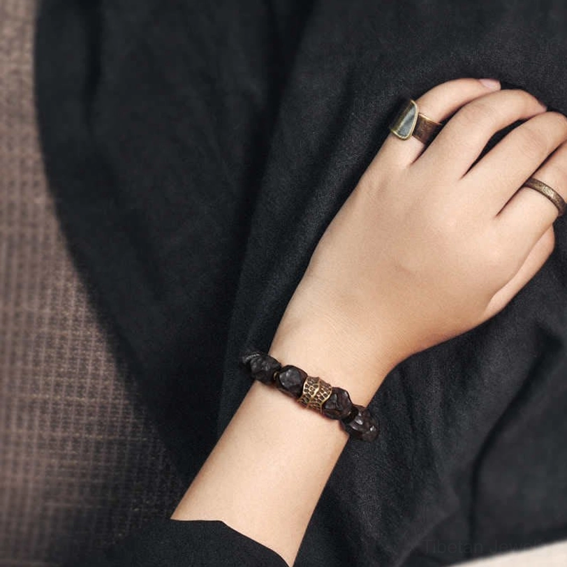 Slim ebony wood copper bracelet styled on wrist with metal rings, demonstrating versatile pairing capability