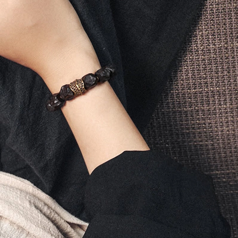 Compact ebony wood copper bracelet worn on wrist with vintage bronze accent, partially covered by sleeve