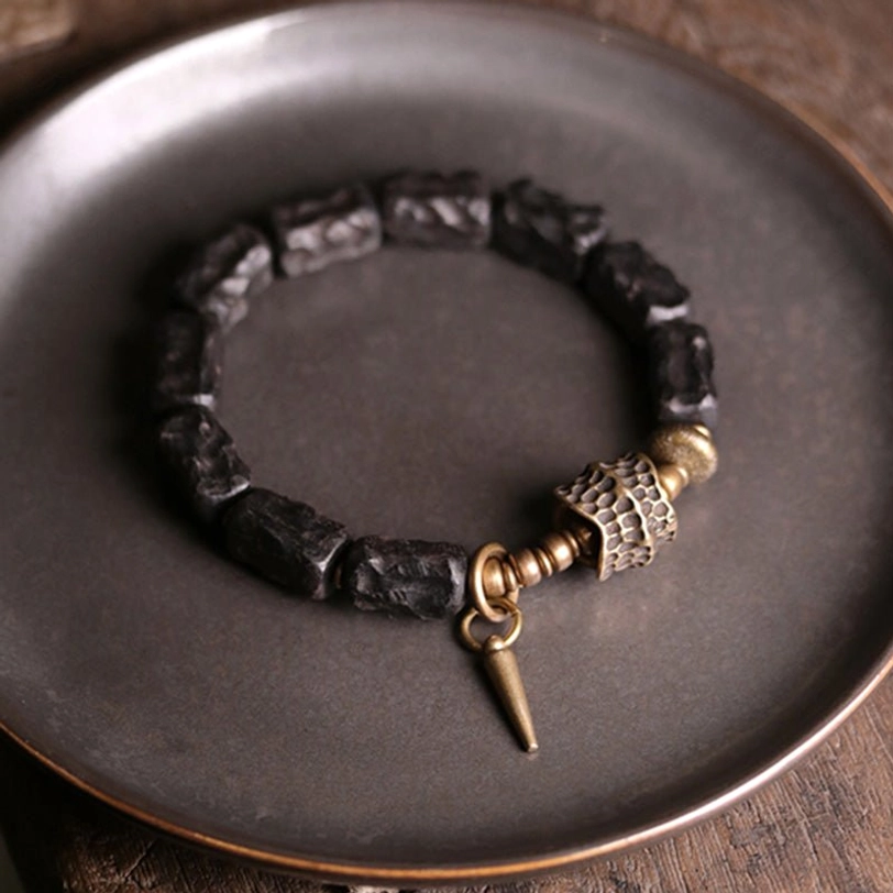 Ebony wood copper protection bracelet with spike pendant on dark metal surface clear view