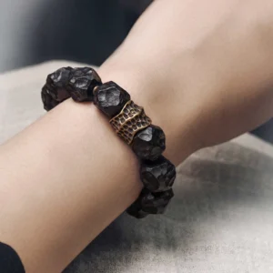 Close-up side view of ebony and copper bracelet worn on wrist, showing hammered texture and vintage bronze accent