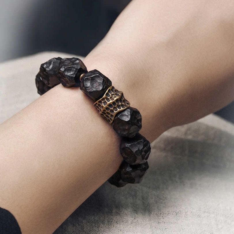 Close-up side view of ebony and copper bracelet worn on wrist, showing hammered texture and vintage bronze accent