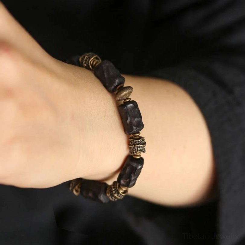 Ebony copper beaded bracelet worn on bare wrist against dark fabric showing detailed bead sequence and comfortable fit