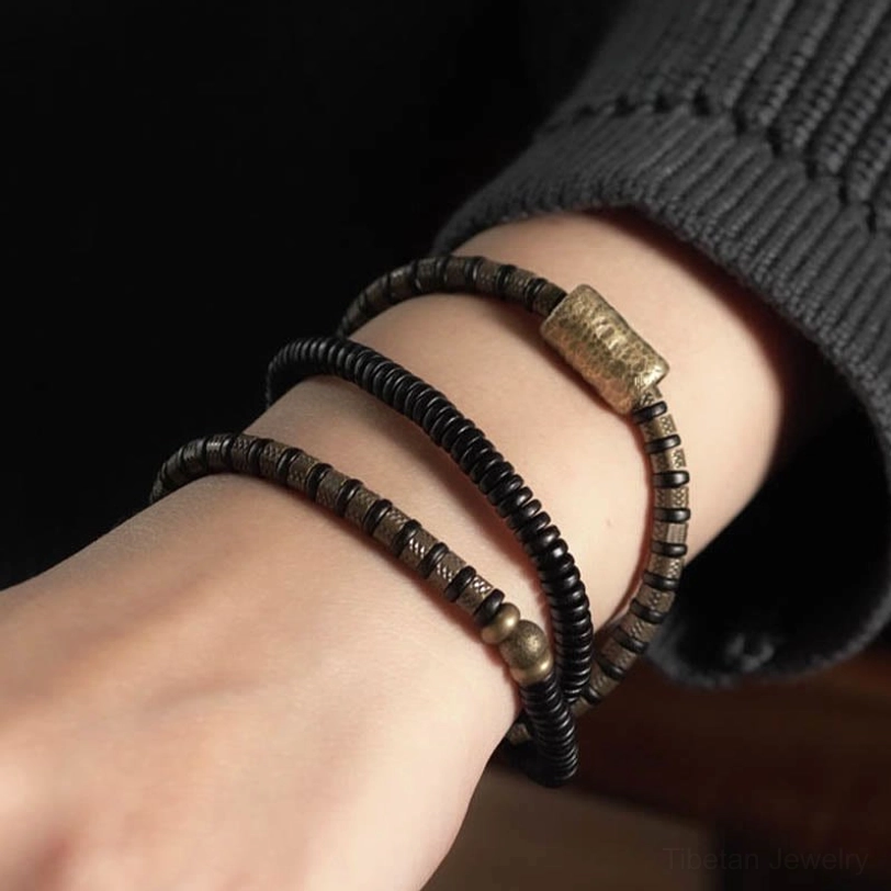 Multi-layered ebony wood copper bracelet worn on wrist with dark sleeve background