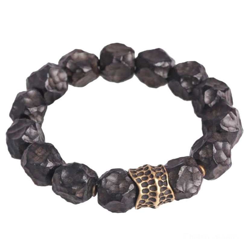 Front facing ebony and copper couple bracelet with large dark beads and central bronze patterned spacer on neutral background