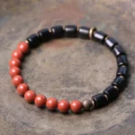 Ebony wood and red jasper gemstone beaded bracelet flat lay with mixed stone beads and copper spacers on vintage wooden surface