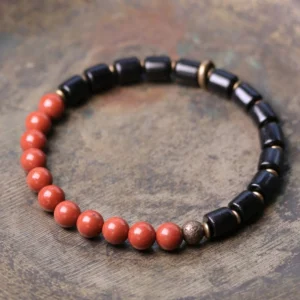 Ebony wood and red jasper gemstone beaded bracelet flat lay with mixed stone beads and copper spacers on vintage wooden surface