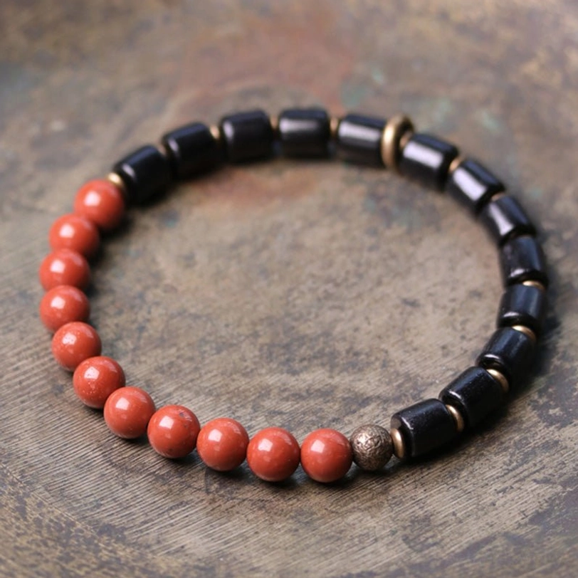Ebony wood and red jasper gemstone beaded bracelet flat lay with mixed stone beads and copper spacers on vintage wooden surface