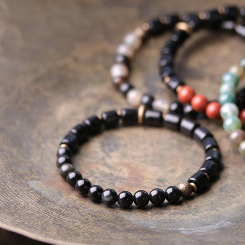 Ebony and black obsidian gemstone bracelet detail showing 6mm bead size with copper metal spacers and elastic cord
