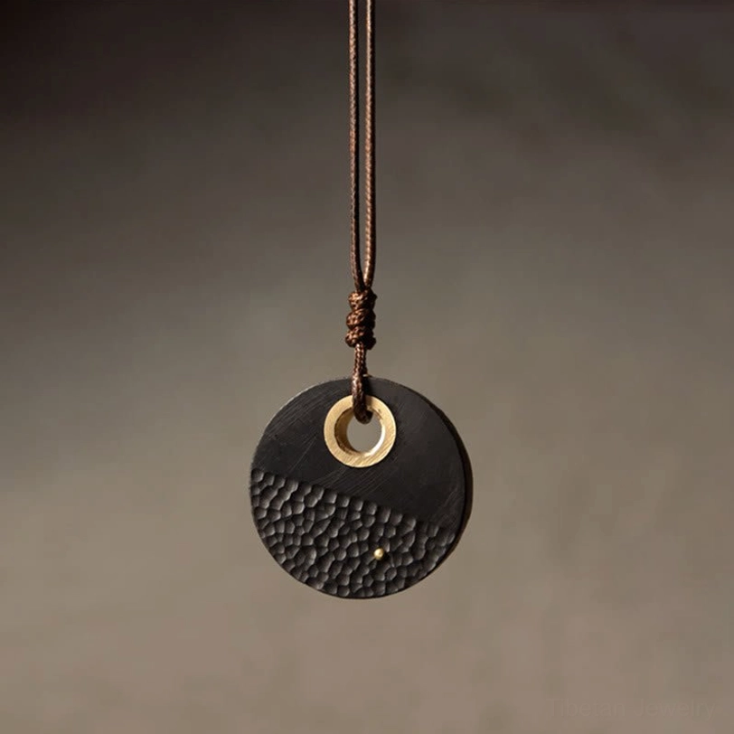 Mini round ebony wood pendant with brass circular opening and braided cord detail