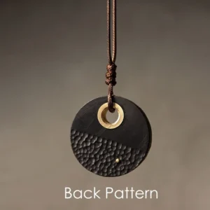 Back side of round ebony wood pendant showing brass dot detail and hammered surface