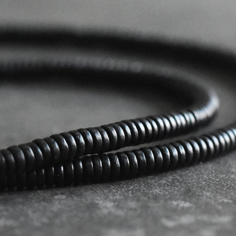 Close-up macro shot of ebony wood disc beads showing texture and finish, tightly arranged two-layer beaded strands