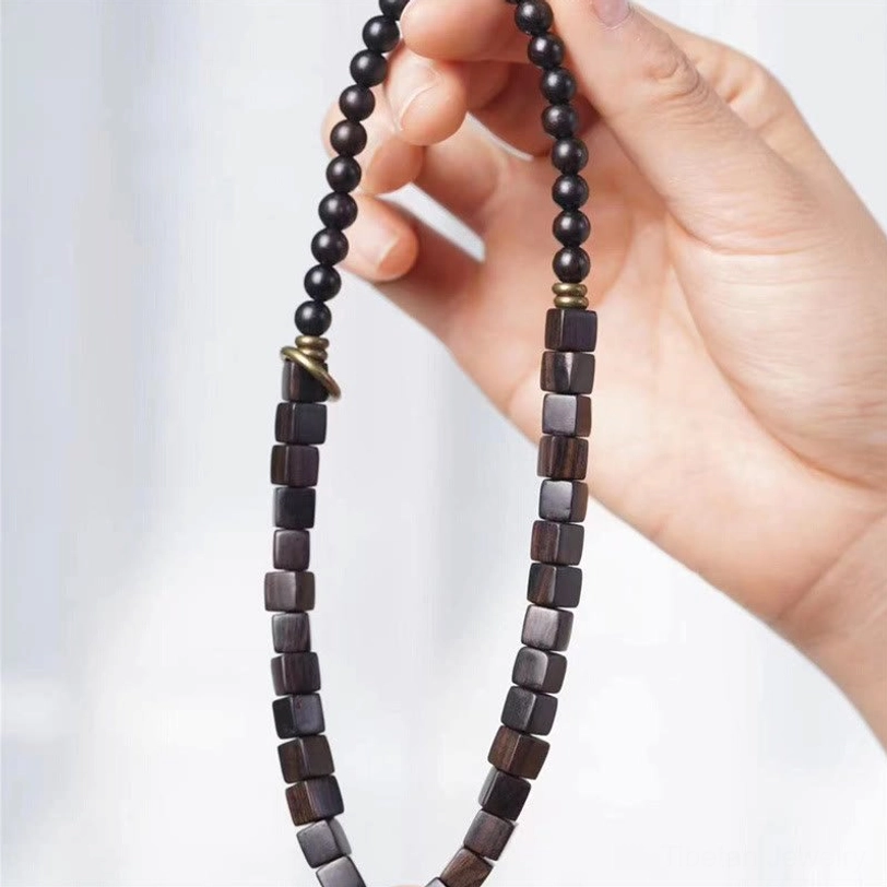 Close-up view of ebony wood beads showing smooth polished finish and metal spacer rings between square and round beads