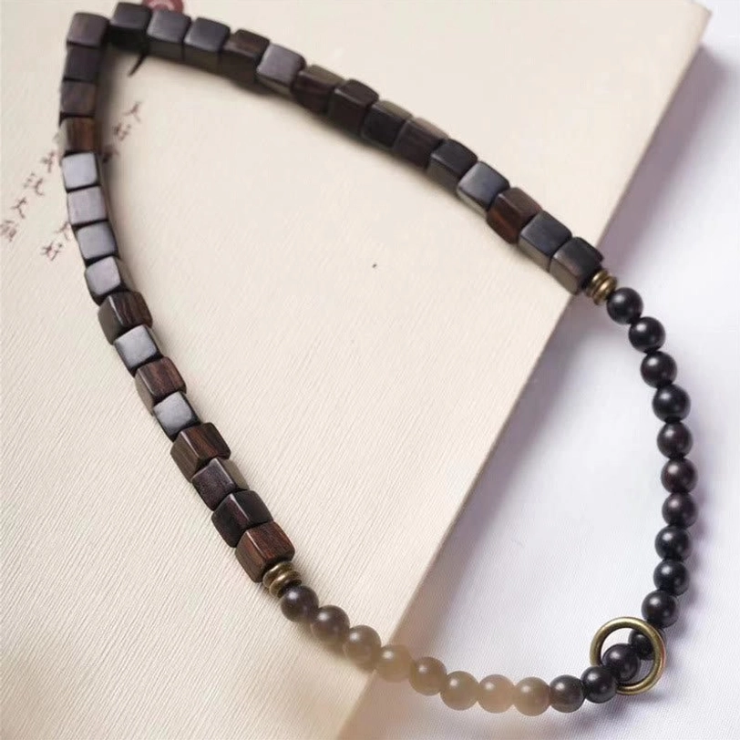 Flat lay overhead view of ebony wood wrap bracelet placed on notebook showing complete two-layer wrap design with metal clasp