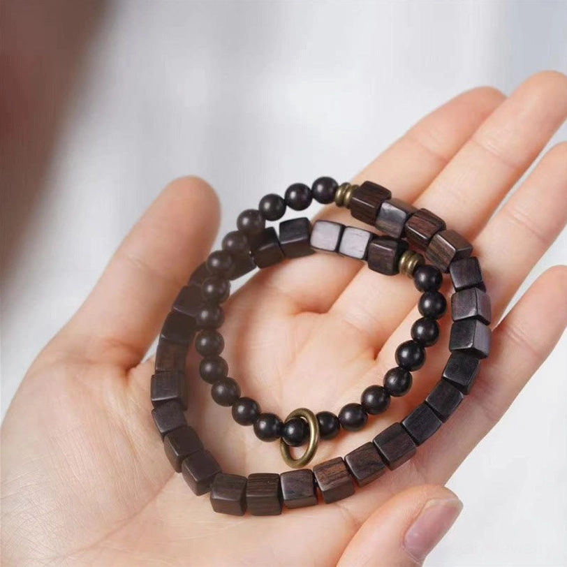 Overhead palm display of ebony wood double wrap bracelet with bronze metal accents highlighting the alternating bead pattern